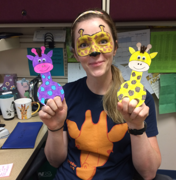 woman with painted face holding paper giraffe in each hand