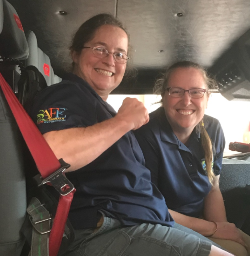 two smiling women in navy blue uniforms sitting in truck